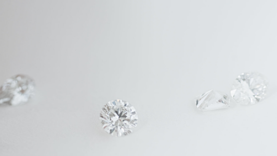 Three polished lab grown diamonds, including a princess cut, displayed on a light grey background.