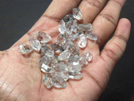 Rough lab grown diamond crystals resting in a person’s palm, the starting material for VVS1 clarity stones.
