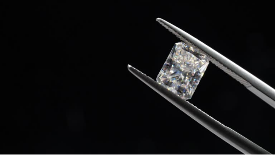Princess-cut lab grown diamond held in tweezers, ideal for D vs E color comparison.