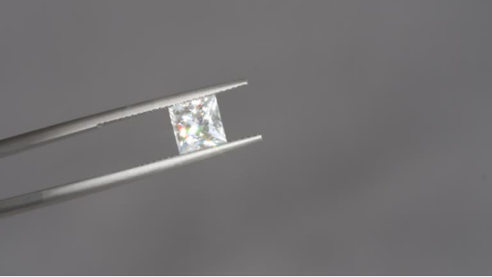 0.25 carat princess-cut lab grown diamond held in precision tweezers.